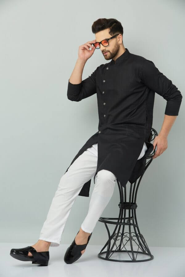 An individual wearing a black kurta and white pants seated on a chair. Indian kurta Teradozz brand
