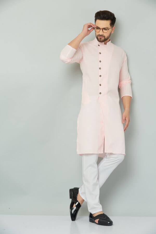 Indian man wearing pink kurta and white pants.